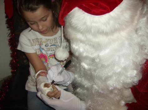 Santa giving his autograph on a little girls cast.